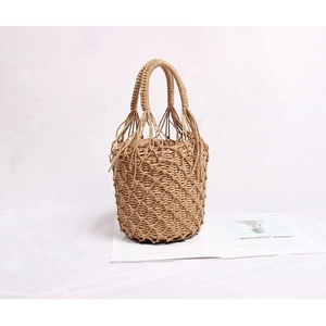 Gros plan détaillé du sac seau en paille tressée avec design ajouré et détails de glands