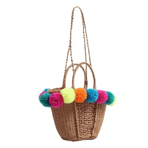 Handmade straw beach tote bag with colorful pom-pom trim and dual shoulder straps