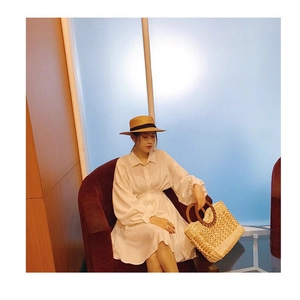Summer resort style woven tote bag with round wooden handles and striped texture detail