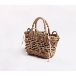 Detail of hand-woven straw tote bag with rustic mesh pattern and inner drawstring pouch