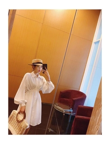 White long-sleeved shirt dress with elastic waist shown with a woven straw beach bag