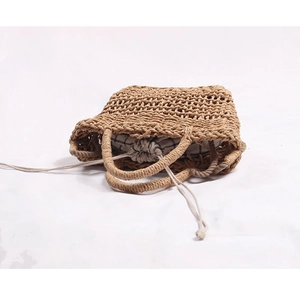 Detailed view of woven straw tote bag with black and white gingham drawstring liner