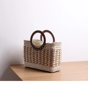 Retro striped straw tote bag with round wooden handles on light wood surface