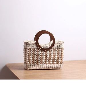 Close-up of woven straw tote bag featuring contrast stripes and round wooden handles