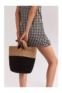 Détail du sac cabas en paille tissé à la main avec base noire et texture naturelle
