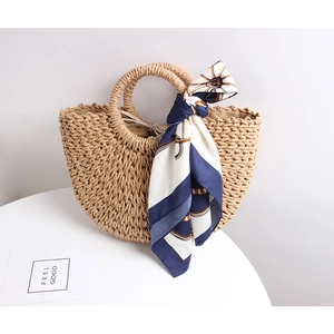 Detail of straw handbag with silk scarf, round handles and secure drawstring liner