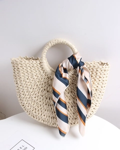 Detail of handmade semi-circle straw bag featuring a silk scarf on the round handle