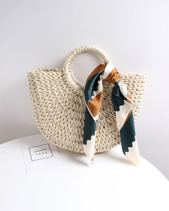 Close-up of semi-circle straw tote bag with rigid round handle and decorative silk scarf