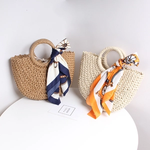 Detailed close-up of straw beach handbags with elegant silk scarves on a minimal table