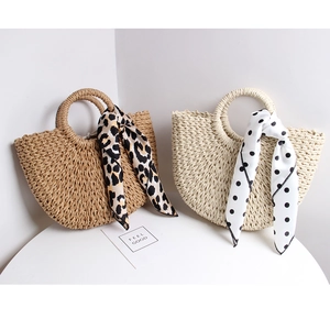 Detail of handmade semi-circular straw bags featuring silk scarves and woven textures