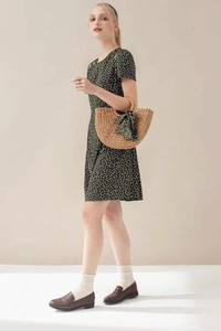 French straw bag styled with a green floral dress and a matching ribbon detail
