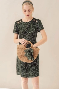 Detail of half-moon straw bag with green floral ribbon and matching cutout dress