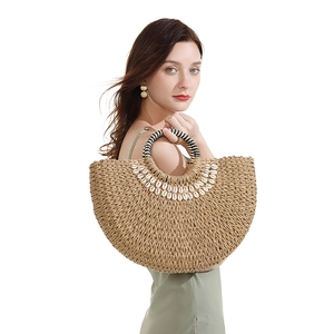 Detail view of woven straw beach bag with shell embellishments and striped round handle