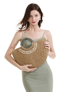 Detailed close-up of straw woven handbag with shell embellishments and striped handles