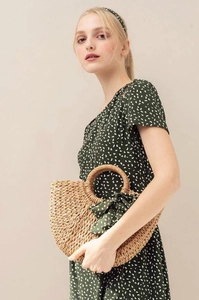 Detail of handmade straw bag with green polka dot scarf and round handle for summer style