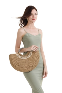 Detail of semi-circular straw bag featuring shell accents and striped handle