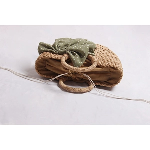 Half-moon straw handbag with a green polka dot bow and inner drawstring lining