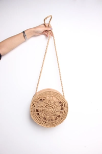 Detail of handwoven round straw bag with hollow radial pattern and woven strap