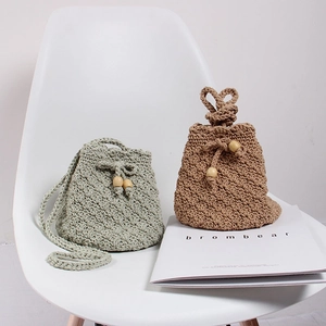 Detail of handmade crochet drawstring bucket bags in sage green and khaki with wooden beads