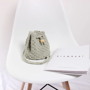 Detail of light green hand-woven knit bucket bag with drawstring and wood beads