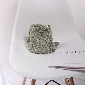 Detail of light green hand-woven bucket bag with shell pattern and drawstring closure
