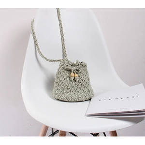 Detailed crochet texture of light green woven crossbody bag with wooden beads drawstrings
