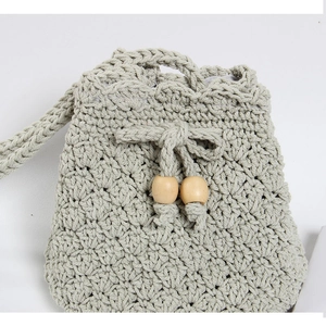 Detail of handmade crochet drawstring bag with wooden beads and woven cotton strap