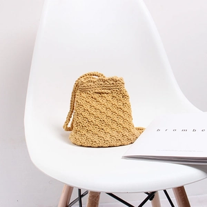 Detail of handmade knit drawstring bucket bag on a minimalist white chair