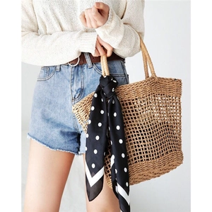 Detail of hand-woven straw tote with elegant black and white polka dot scarf handle