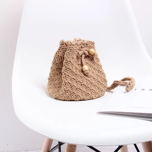 Detail of handmade knit drawstring bucket bag with wooden beads on a white chair