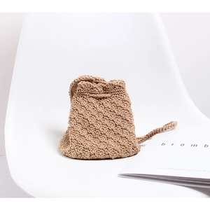 Close-up of handmade crochet crossbody bag with drawstring closure on a white chair