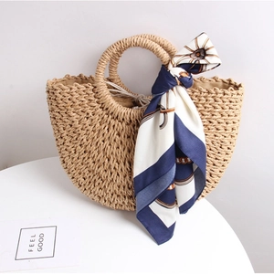 Handcrafted semicircular straw tote bag with elegant silk scarf for beach vacations