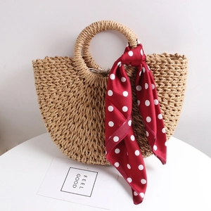 Handmade half-moon straw beach bag with round handles and a red polka dot silk scarf