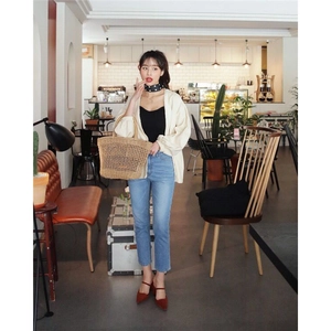 French chic outfit with hollow straw tote bag, beige cardigan, and denim pants in cafe
