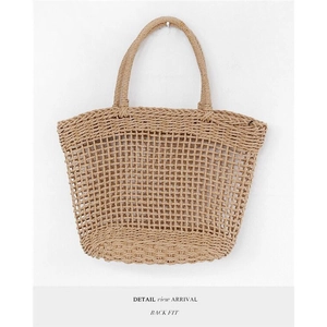 Detail view of handmade hollow straw tote bag with mesh texture and reinforced base
