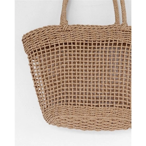Close-up of hand-woven hollow grid pattern on a natural straw beach tote bag