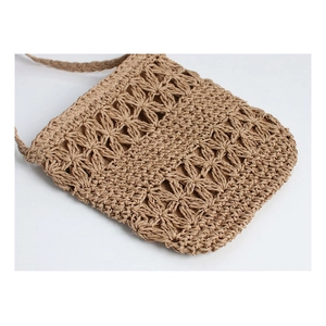 Detail of hollow floral crochet pattern on handmade straw crossbody beach bag