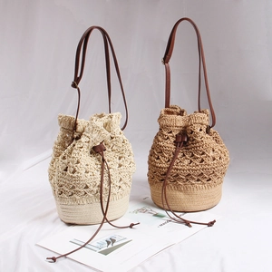 Detail of bohemian straw bucket bags with hollow flower pattern and leather drawstrings