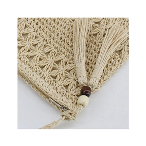 Detailed view of woven floral pattern with metal zipper and bead tassels on straw bag