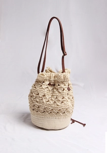 Close-up of hollow flower weave and drawstring closure on a straw bucket bag