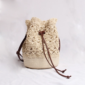 Handmade cream straw bucket bag with floral crochet patterns and leather drawstring
