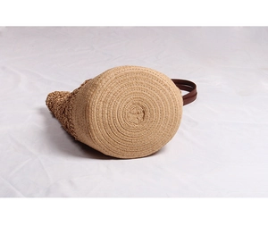 Macro shot of circular spiral weave base on handmade straw tote bag with brown leather handle