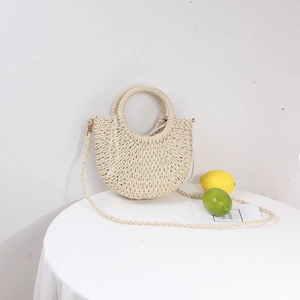 Detail of a straw beach bag with ring handles and a drawstring pouch closure on a white table