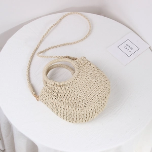 Detail of hand-woven beige straw bag with round handles and long crossbody strap