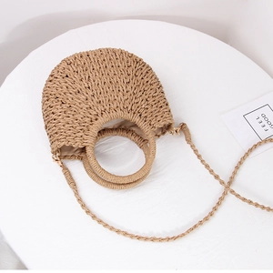Detailed close-up of handmade semi-circular straw woven bag texture and round handles