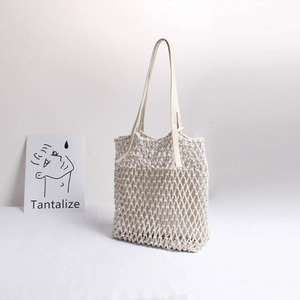 Detail of cream woven mesh beach bag with smooth leather shoulder straps and net texture
