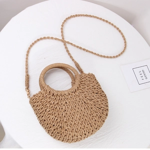 Detail of hand-woven straw crossbody bag with circular handles on white background