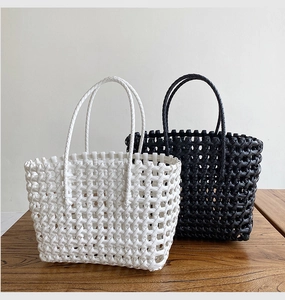 Detail of woven straw tote bags in black and white with hollow texture and round handles