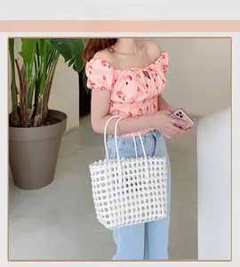 Close-up of white woven tote bag with hollow square mesh and smooth double handles
