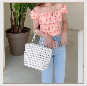 Detailed view of a white hollow woven tote bag styled with a summer peach print top
